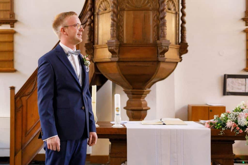 Emotionaler Moment bei der kirchlichen Trauung in der Evangelischen Kirche am Markt in Xanten: Das Brautpaar steht gemeinsam am Altar, die Braut im weißen Spitzenkleid mit Schleier, der Bräutigam im eleganten Anzug. Gäste verfolgen die Zeremonie aufmerksam in der festlich geschmückten Kirche. Dieses Foto zeigt die authentische Hochzeitsreportage vom Hochzeitsfotograf Xanten.