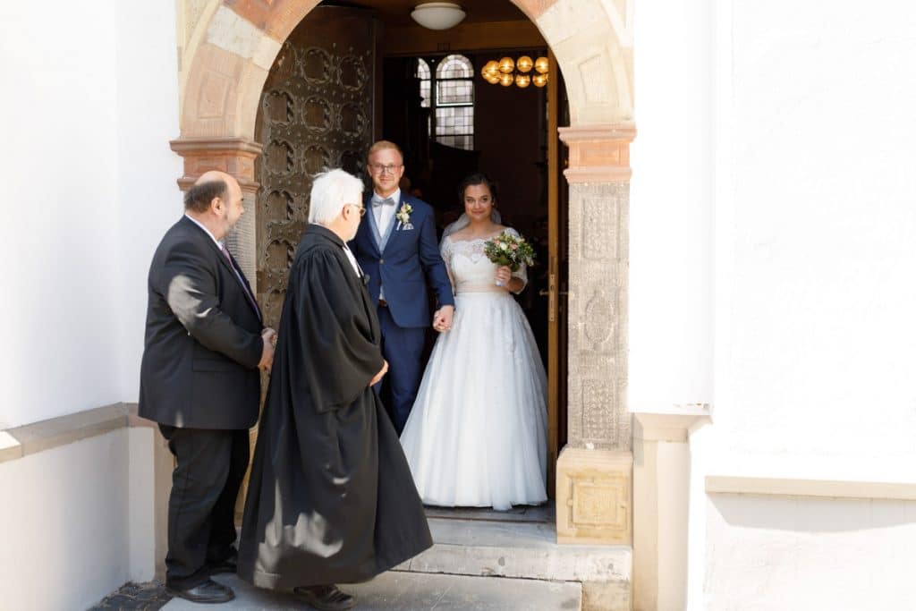 Emotionaler Moment bei der kirchlichen Trauung in der Evangelischen Kirche am Markt in Xanten: Das Brautpaar steht gemeinsam am Altar, die Braut im weißen Spitzenkleid mit Schleier, der Bräutigam im eleganten Anzug. Gäste verfolgen die Zeremonie aufmerksam in der festlich geschmückten Kirche. Dieses Foto zeigt die authentische Hochzeitsreportage vom Hochzeitsfotograf Xanten.