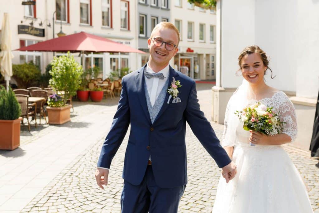 Emotionaler Moment bei der kirchlichen Trauung in der Evangelischen Kirche am Markt in Xanten: Das Brautpaar steht gemeinsam am Altar, die Braut im weißen Spitzenkleid mit Schleier, der Bräutigam im eleganten Anzug. Gäste verfolgen die Zeremonie aufmerksam in der festlich geschmückten Kirche. Dieses Foto zeigt die authentische Hochzeitsreportage vom Hochzeitsfotograf Xanten.