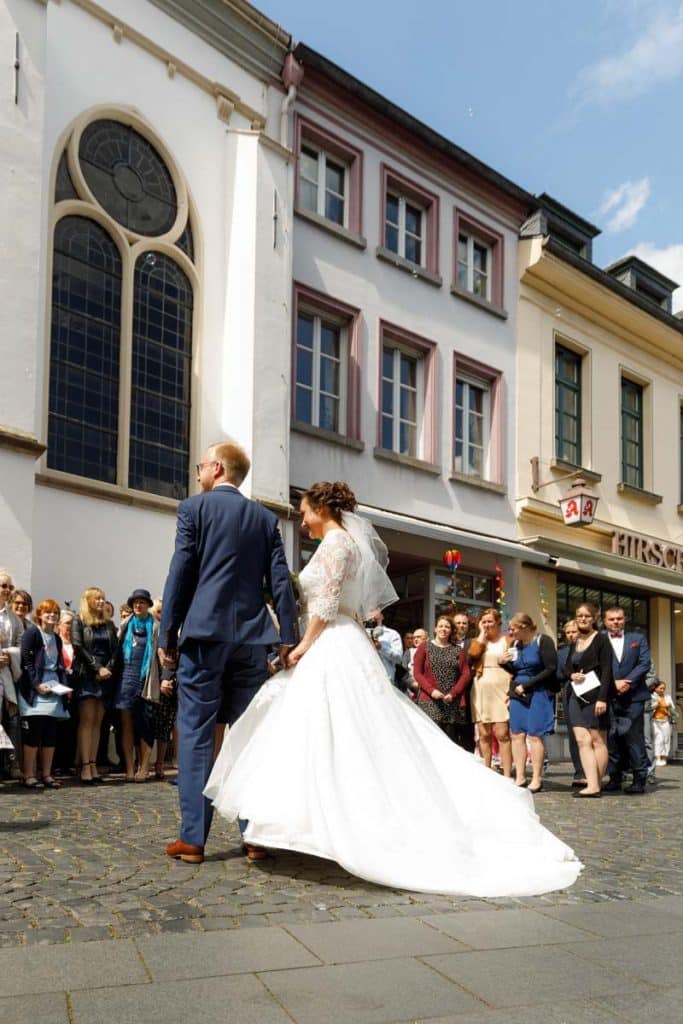 Emotionaler Moment bei der kirchlichen Trauung in der Evangelischen Kirche am Markt in Xanten: Das Brautpaar steht gemeinsam am Altar, die Braut im weißen Spitzenkleid mit Schleier, der Bräutigam im eleganten Anzug. Gäste verfolgen die Zeremonie aufmerksam in der festlich geschmückten Kirche. Dieses Foto zeigt die authentische Hochzeitsreportage vom Hochzeitsfotograf Xanten.