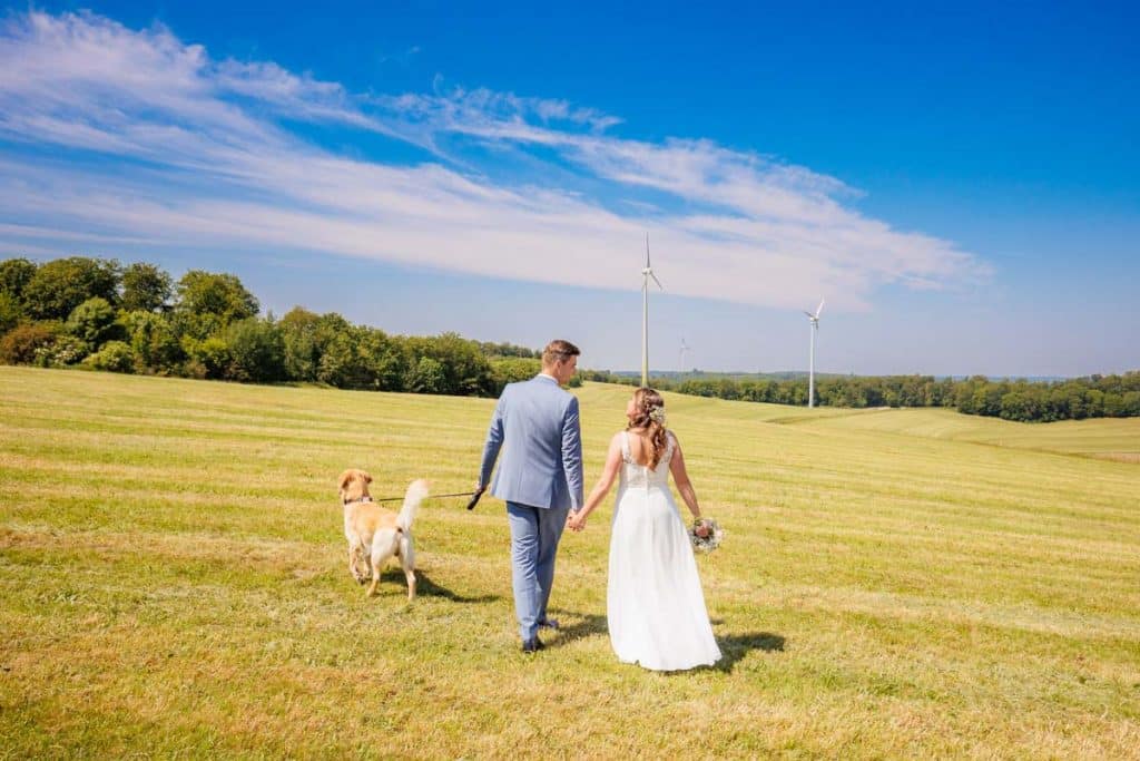 Romantisches Portraitshooting mit Hund und Diana und Hendrik im Grünen des Sauerlands. Die hügelige Landschaft, Wiesen und Felder boten eine malerische Kulisse für natürliche, emotionale Hochzeitsfotos. Authentische Aufnahmen voller Liebe und Glück, fotografiert vom Hochzeitsfotograf Sauerland.