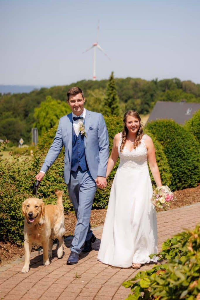 Romantisches Portraitshooting mit Hund und Diana und Hendrik im Grünen des Sauerlands. Die hügelige Landschaft, Wiesen und Felder boten eine malerische Kulisse für natürliche, emotionale Hochzeitsfotos. Authentische Aufnahmen voller Liebe und Glück, fotografiert vom Hochzeitsfotograf Sauerland.