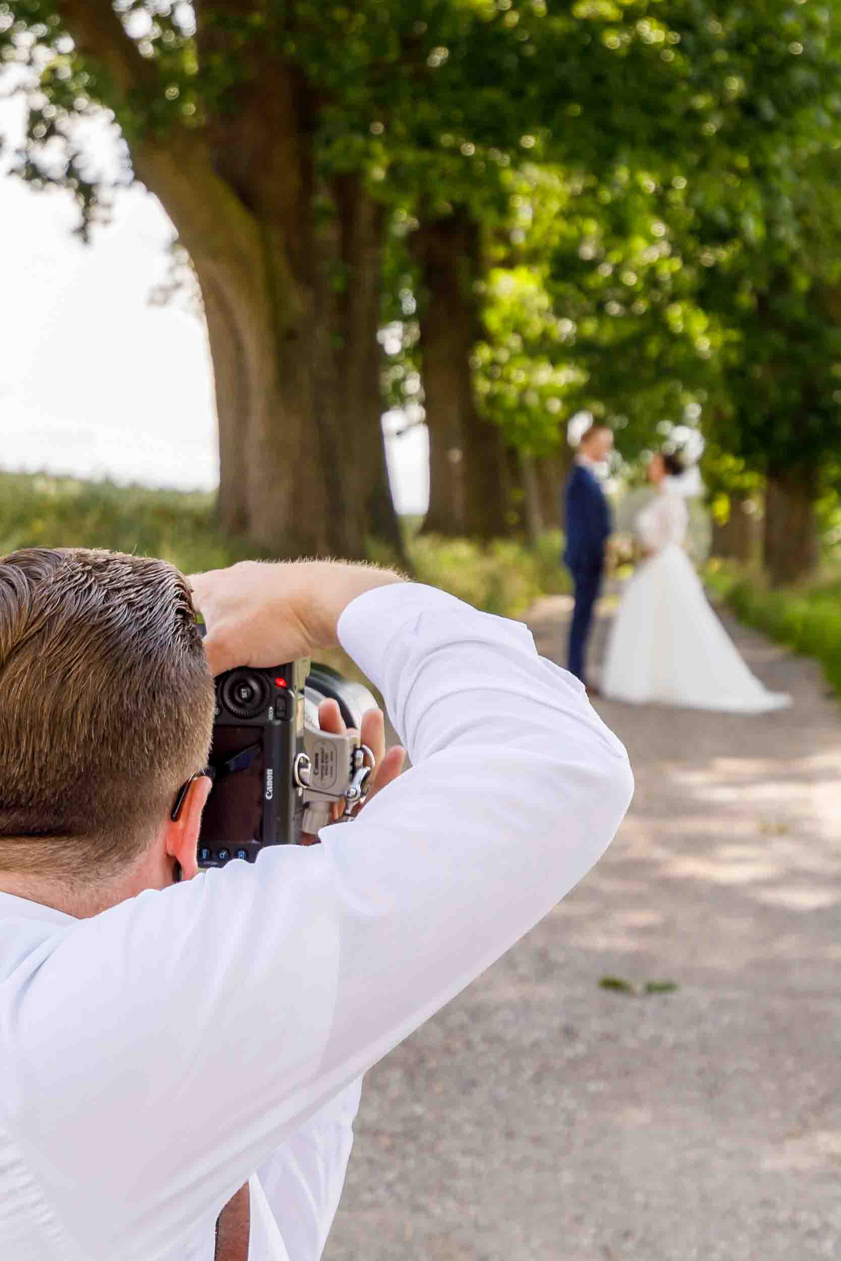 Portrait von Hochzeitsfotograf Martin Valk aus Duisburg mit Kamera und Brautpaar.